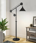 Tall Pulley System Floor Lamp With Metal Shade In Blackened Bronze Finish Adjustable Arc Lighting For Home Office Living Room Or Bedroom Mid Century Modern Style With Dope Industrial Vibe next to a plant and a desk in a bright room.