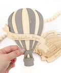 Wooden Hot Air Balloon Monthly Milestone Cards For Babies, My First Year Sign held by hand, featuring "The Adventure Begins" text