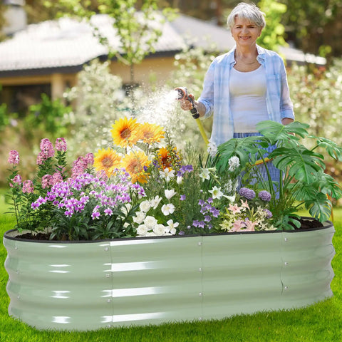 Woman watering flowers in a Galvanized Raised Garden Bed Outdoor 4x2x1 Ft Oval Planter With Safety Edging And Gloves, Avocado Green Finish.
