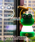 Green frog-shaped LED lantern hanging on window for Owl Themed Kid Friendly LED Lantern And Headlamp Set Battery Powered Lit Night Light For Emergency And Camping Lightweight Tent Lamp For Children Perfect For Hurricanes And Backyard Adventures.
