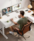 Person using L Shaped Electric Standing Desk With Four Wooden Drawers 55 Inch Height Adjustable Corner Desk With Power Outlets Space Saving Sit Stand Table For Home Office White Ideal For Any Space in home office.