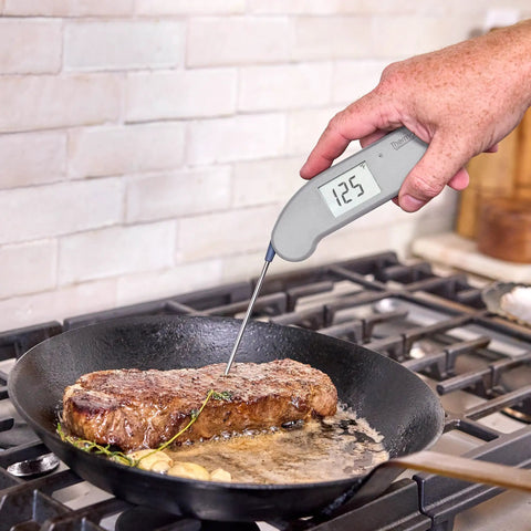Top Rated No. 1 Instant-Read Thermometer For Precision Cooking, One-Second Read, measuring steak temperature in skillet.