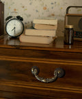 Front view of Six Pack Vintage Drop Bail Cabinet Handles in Antique Brass Finish on a wooden dresser drawer, 3-1/2 inch hole centers.