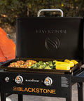 28 Inch Griddle With Protective Hood And Counter Height Side Shelves In Powder Coated Steel For Outdoor Grilling, 524 Square Inches Of Cooking Space; cooking vegetables and corn in outdoor setting.