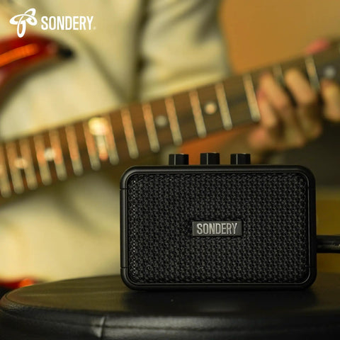 Ultra Portable 5W Mini Guitar Amp For Electric Guitars With Two Speakers And Rechargeable Battery on a stool