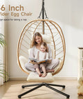 Mother and child sitting in a wicker rattan hanging egg chair with cushion, 36-inch size, indoors with plants and toys.