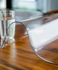 Clear Plastic Table Cover Protector 60x36 Inches Vinyl Tabletop Shield on wooden table with glass of water