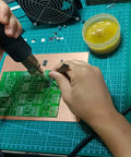 Hands soldering a circuit board using the Advanced SMD and SMT Soldering Practice Kit for Pro Electronics Hobbyists DIY Training Board With 313 Components And 1079 Precision Solder Points EK8489.