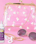 Clear Gel Tacky Glue for Crafts and Slime, 4 oz bottle next to a clear purse with floral decor, sunglasses, and gold chain on pink background