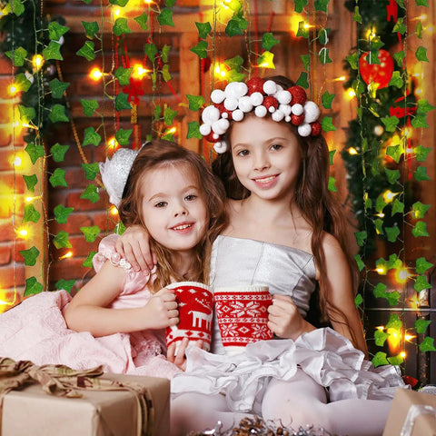 Two children with mugs in front of fake ivy vines with 80 LED string lights, cozy indoor setting, decorative background.