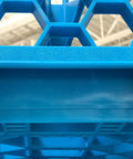 Close-up of blue polypropylene OptiClean NeWave 20-compartment glass rack with hexagonal design and two extenders.