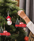Three Pack Totally Vintage Red Truck Christmas Ornaments With Mini Christmas Trees Handcrafted Red Plastic Truck Models being hung on tree