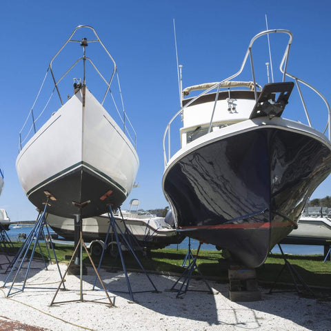 Two boats on stands in a marina, showcasing areas ideal for Dockside Ready Marine Grade Lubricant And Penetrating Oil For Boats And Gear.