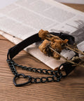 Dope Gothic Punk Leather Choker Necklace Featuring Adjustable Black Heart Chain For Edgy Grunge Emo Style And Alt Streetwear Vibes laid on wooden surface with dried flowers.