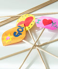 Premium Unfinished Hardwood Dowel Rods 1/4 X 12 Inches Ten Pack holding colorful paper signs for DIY crafts.