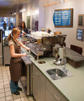 Barista using a Commercial Bar And Pantry Faucet 2.2 GPM Chrome Finish With M-Dura Cartridge in a busy kitchen setting