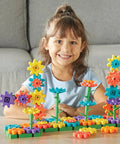 Child playing with 101 Piece Gear Building Set For Kids So They Can Build Twisting Gardens While Learning Cause Effect Sequencing And Early Engineering Hands On STEM Construction Toy Montessori Inspired Kid Friendly Fine Motor Play And Educational Engineering Gift on table.