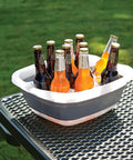 Collapsible Tub For Washing And Soaking, A Space Saving Foldable Utility Basin With Raised Feet For Quick Draining holding bottles on a table