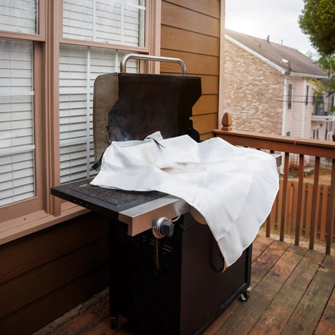 Emergency Fire Blanket 40 By 40 Inches, Woven Fiberglass Fire Shield, covering a grill on a wooden deck for fire suppression.