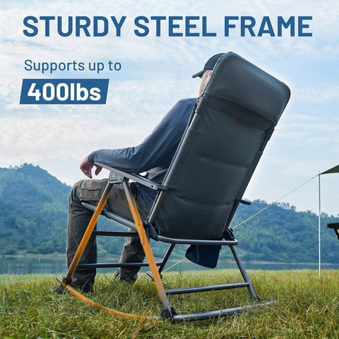 Side view of a person seated on an oversized folding rocking camping chair with padded high back, supporting up to 400 lbs, by a lake
