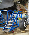 Aviation platform with stairs and wheels underneath an aircraft, showing landing gear maintenance area.
