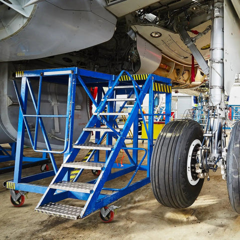 Aviation platform with stairs and wheels underneath an aircraft, showing landing gear maintenance area.