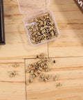 120 Pcs 3D Printing Brass Heat Set Inserts Knurled M3x5.7x4.6Mm in open plastic box with scattered inserts on wooden surface