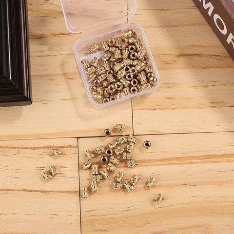 120 Pcs 3D Printing Brass Heat Set Inserts Knurled M3x5.7x4.6Mm in open plastic box with scattered inserts on wooden surface