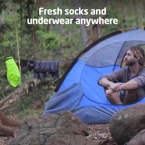 Pocket Friendly Travel Laundry Sack With A Built In Washboard Surface For Quickly Scrubbing Down Socks And Undies While Backpacking Or Hitting The Road Without Lugging Heavy Machines Or Clunky Gear hanging outside a tent.