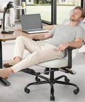 Person relaxing in an ergonomic office chair with footrest and mesh back, adjustable headrest and armrests, gray, in home office