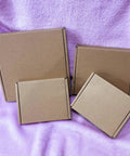 Heavy Duty 5X4X1 Small Shipping Boxes 50 Pack stacked on purple fabric, showcasing brown E flute cardboard material.