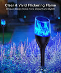 Solar Outdoor Lights 6 Pack Tiki Torches With Flickering Flame in garden at night with blue glow, Decorative Garden Pathway Yard Decor.