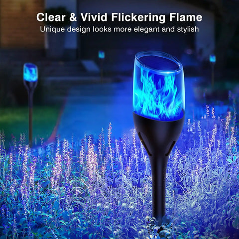Solar Outdoor Lights 6 Pack Tiki Torches With Flickering Flame in garden at night with blue glow, Decorative Garden Pathway Yard Decor.
