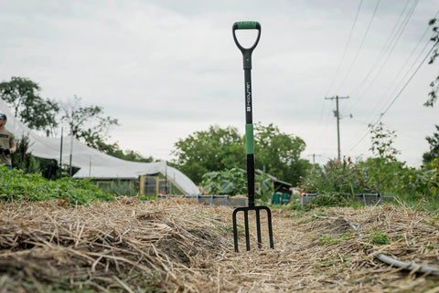 Rugged Heavy Duty Digging Fork With Carbon Steel Head And Fiberglass Core in garden, showing short handle and no-slip H-Grip.