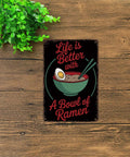 Life Is Better With Ramen Bowl Vintage Metal Sign Tin Wall Art Poster on wooden surface with greenery beside