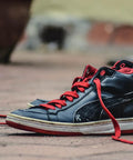 Black and red sneakers on pavement, showcasing shoe design and color contrast.