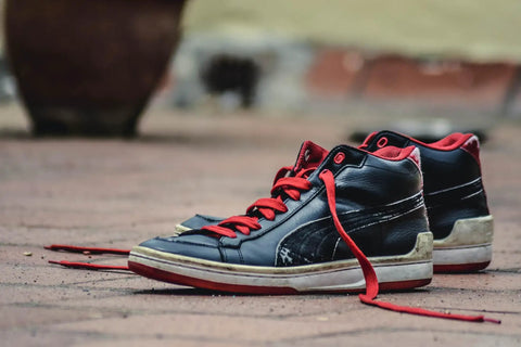 Black and red sneakers on pavement, showcasing shoe design and color contrast.