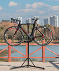 Ebike Repair Stand For Home Shop And Mechanics Heavy Duty Bike Workstand lifting road bike by lake with cityscape background
