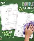 Hand erasing 9x12 dry erase sheets on green background, showcasing multiplication practice for classroom math manipulatives.