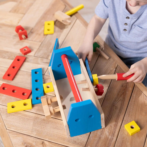 Child playing with Take Along Tool Kit Wooden Construction Toy Set For Little Builders including hammer, boards, and screws