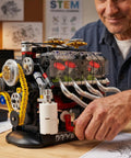 V8 Engine Model Kit For STEM Builders A Real Hands On Build And Drive Display With Full Internal Motion View And Dual Mode Operation Letting You Assemble Observe Run And Show Off A Lean Legit High Tech Mechanical Playground. man assembling plastic V8 model kit with clear engine cover