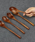 Six Piece Japanese Natural Wooden Spoons Set For Cooking And Eating Great For Stirring Tea Honey Soda Dessert And Nonstick Pots Made From Nanmu Wood About Eight Point Seven Eight Inches Long Eco Friendly Kitchen Tools displayed on grey fabric with a hand holding one spoon