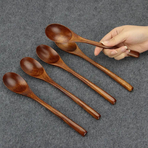 Six Piece Japanese Natural Wooden Spoons Set For Cooking And Eating Great For Stirring Tea Honey Soda Dessert And Nonstick Pots Made From Nanmu Wood About Eight Point Seven Eight Inches Long Eco Friendly Kitchen Tools displayed on grey fabric with a hand holding one spoon
