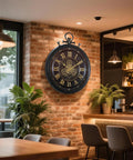 24 Inch Moving Gear Wall Clock Oversized Industrial Steampunk Decor With Big Numerals Carbon Black Finish mounted on a brick wall.