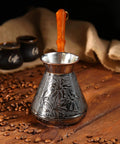 Copper Turkish Greek Arabic Engraved Coffee Pot For Go-To Stovetop Brew With Wooden Handle Cezve Ibrik Briki on wooden table.