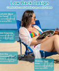 Woman sitting on 2 Pack Lightweight Low Beach Chairs With Breathable Mesh Back, Folding Portable Sand Chairs With Cup Holder, Ultralight 6 Lb Each, Heavy Duty 300 Lb Capacity, Easy Carry For Camping And Outdoor Use, Blue at the beach.
