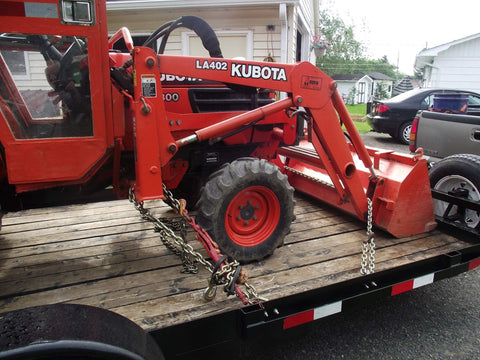 Ratcheting Chain Binder Three Eighths To One Half Inch Four Pack Load Binders securing orange farming equipment on trailer.