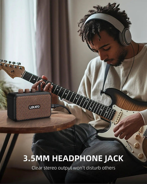 Musician using Portable 5W Mini Guitar Amplifier With Dual Speakers, Rechargeable Bluetooth Practice Amp, compact brown unit on table.