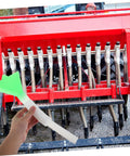 Hand holding Seed Spreader Tube For Corn Planters 1 Set Plastic Seeder Replacement Tube in front of red planter machine