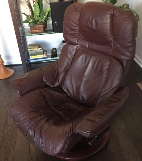 Brown leather recliner chair positioned on wooden floor with soft cushions and supportive back for comfort and relaxation.